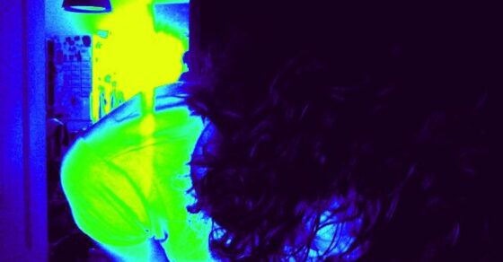 Autorretrato de Roser Amills inclinada, de espaldas, con la melena rizada y un filtro de color azul y amarillo