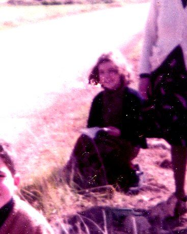 Roser Amills de niña, sentada en el campo, en una fotografía antigua de tonos rosados