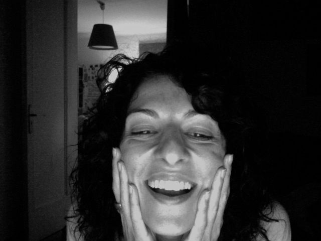 Autorretrato en blanco y negro de Roser Amills riendo, con las manos en las mejillas