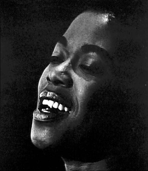 Fotografía de Ed van der Elsken en blanco y negro: primer plano de una mujer cantando