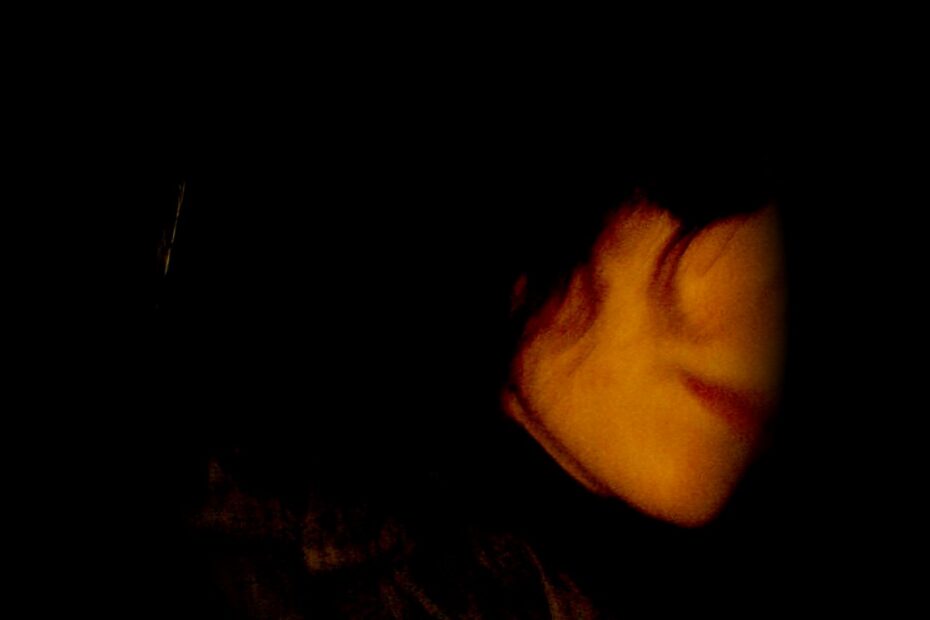 Autorretrato en la oscuridad: rostro de Roser Amills de perfil, apenas iluminado, con los labios rojos