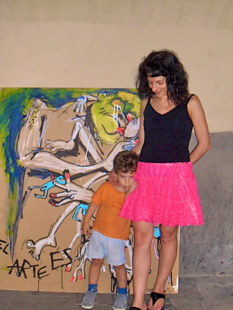 Roser Amills, con top negro y falda rosa, junto a un niño con camiseta naranja delante de la obra «El arte es basura»