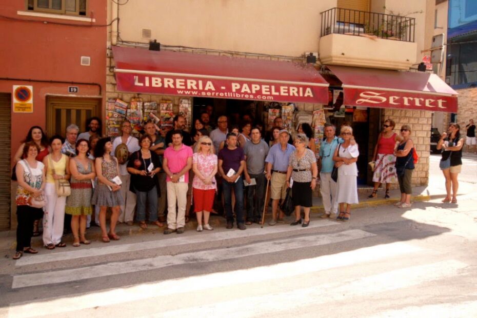 Grupo de autores y vecinos posando en la acera frente a la Librería-Papelería Serret, en Vall-de-roures, el día de la Trobada