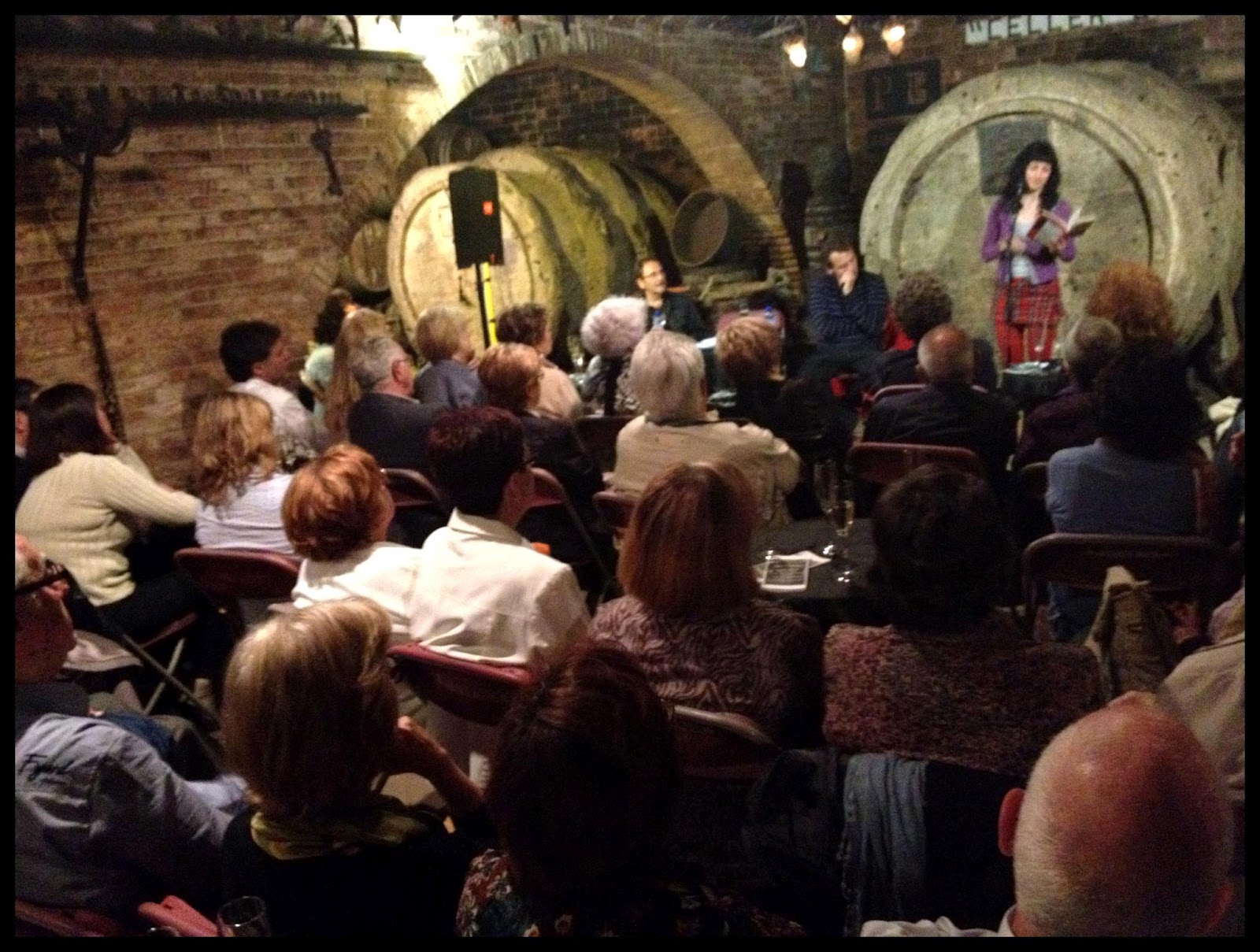 Roser Amills recitant davant el públic assegut en una cava amb voltes de maó, a Caves Gramona