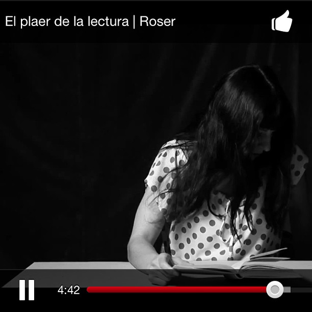 Roser Amills, en blanco y negro y con blusa de lunares, lee un libro sobre una mesa con el pelo cubriéndole la cara