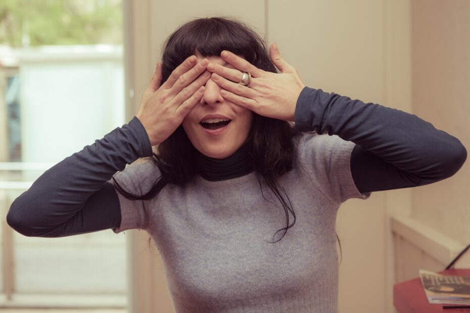 Roser Amills se tapa los ojos con las manos y abre la boca, con jersey gris y mangas oscuras