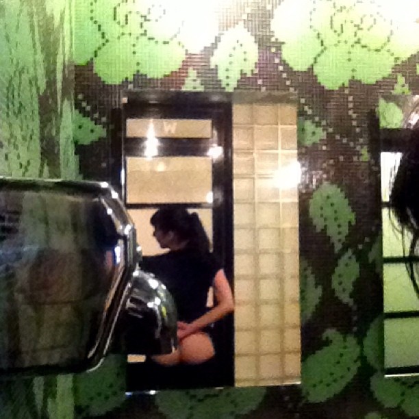Reflejo en un espejo ante una pared de azulejos verdes