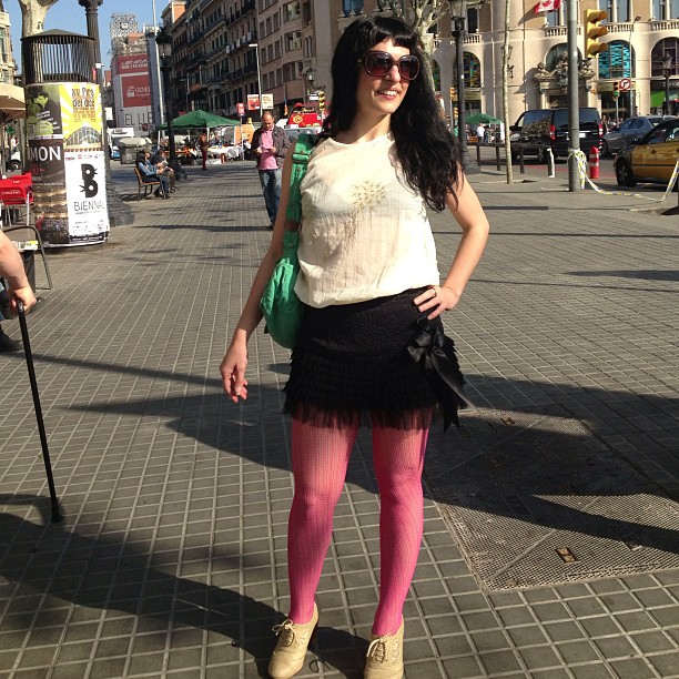 Roser Amills de cuerpo entero en la calle, con blusa blanca, falda negra y medias rosas, en la mañana de Sant Jordi 2013