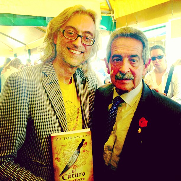 Víctor Amela con su novela El cátaro imperfecto junto a Miguel Ángel Revilla, con una rosa en la solapa