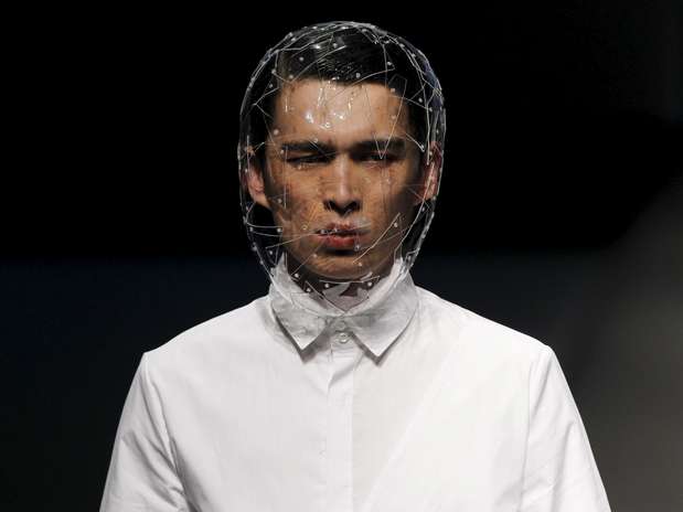 Hombre con camisa blanca y la cabeza cubierta por una malla de alambre, sobre fondo negro