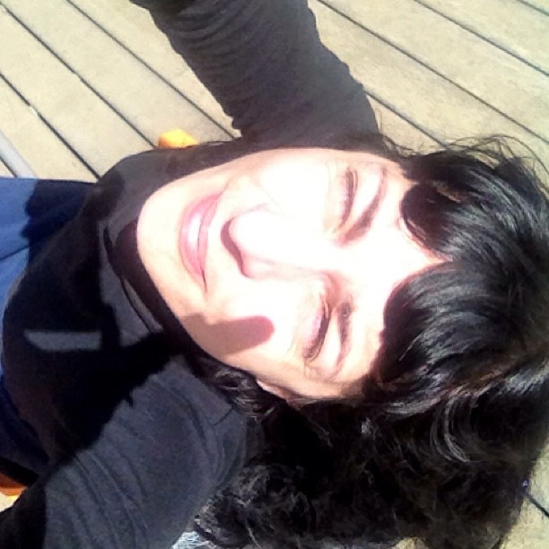 Roser Amills tumbada sobre una terraza de madera, sonriendo con los ojos cerrados al sol de primavera