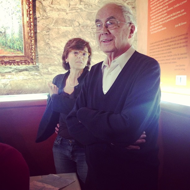 Josep Maria Espinàs, con jersey oscuro y los brazos cruzados, junto a una mujer, en un restaurante