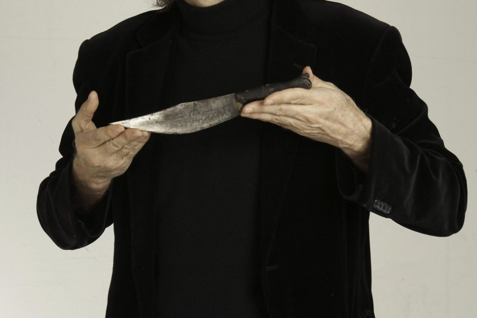 Víctor Amela vestido de negro sostiene el cuchillo que ilustra la cubierta de El cátaro imperfecto