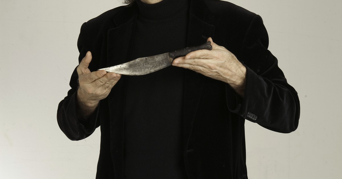 Víctor Amela vestido de negro sostiene el cuchillo que ilustra la cubierta de El cátaro imperfecto