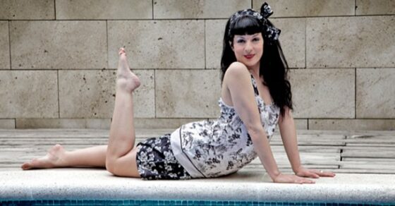 Roser Amills sentada junto a una piscina, con vestido estampado y lazo en el pelo