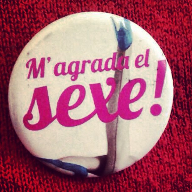 Chapa blanca y rosa de «M'agrada el sexe!» sobre un jersey rojo