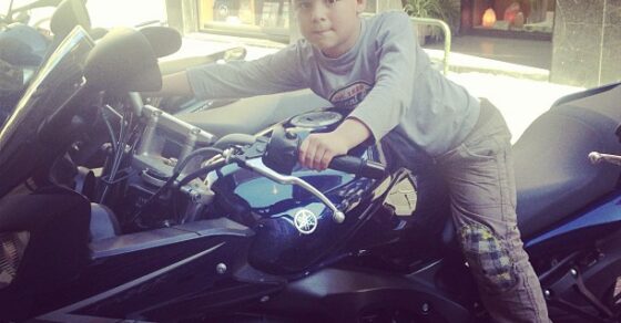 Niño subido a una moto aparcada en una tienda