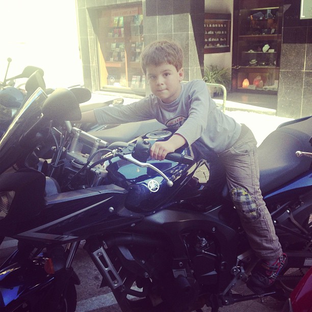 Niño subido a una moto aparcada en una tienda