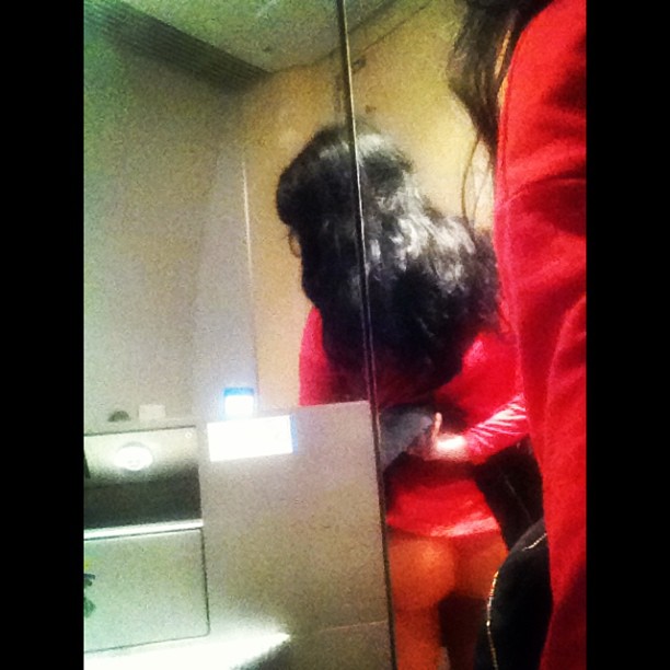 Roser Amills con jersey rojo de espaldas, reflejada en el espejo de un lavabo del AVE