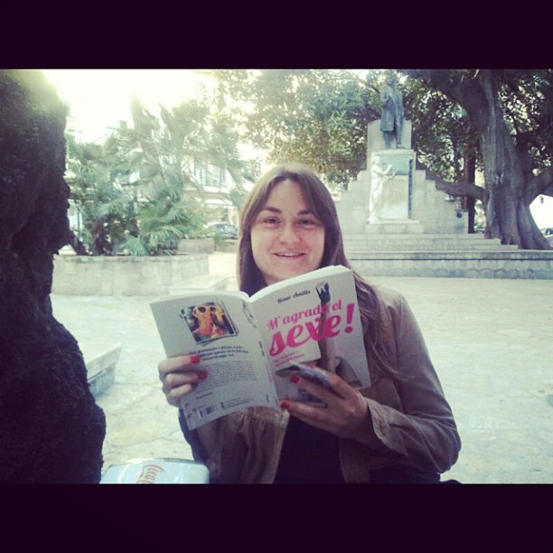 Lectora con un ejemplar de M'agrada el sexe! en una plaza de Mallorca