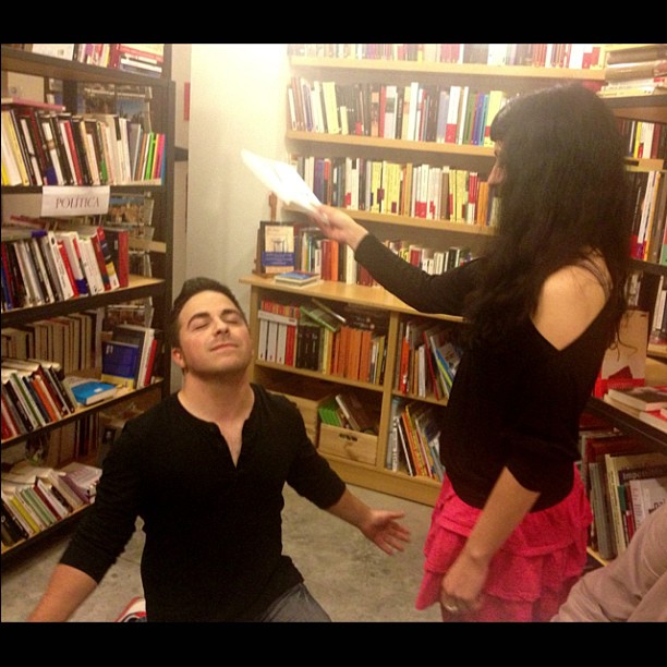 Un hombre de rodillas ante Roser Amills, que sostiene unos papeles, en la librería de Girona