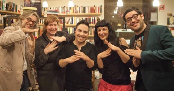 Grupo con Roser Amills y Víctor Amela haciendo un gesto con las manos en la librería de Girona