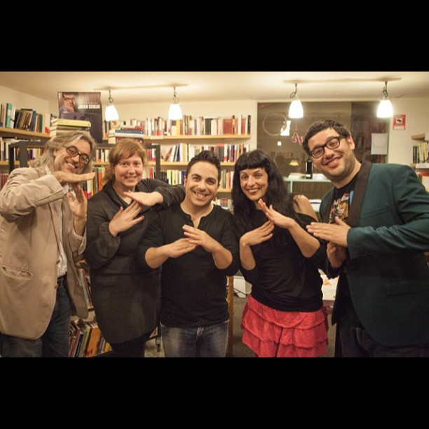 Grupo con Roser Amills y Víctor Amela haciendo un gesto con las manos en la librería de Girona
