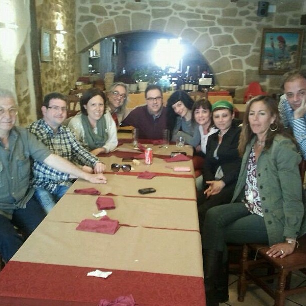 Comida de grupo en torno a una larga mesa en un restaurante de piedra