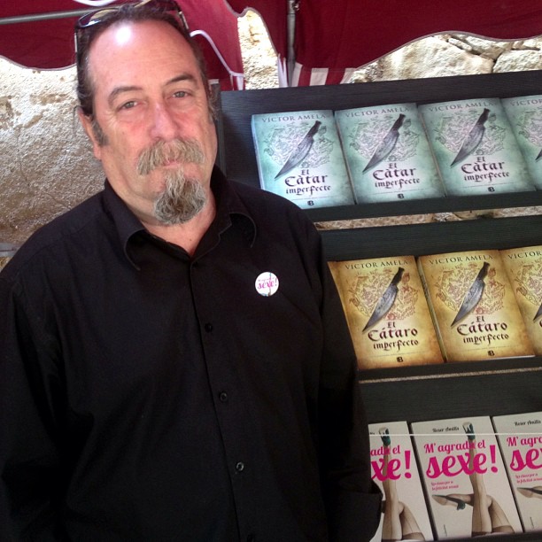Isidre Garrido con una chapa de M'agrada el sexe!, ante una estantería con libros