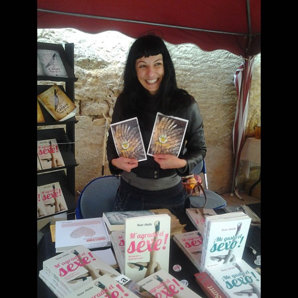 Roser Amills con dos folletos en las manos ante la mesa de libros de la Fira de la Mel de Arnes