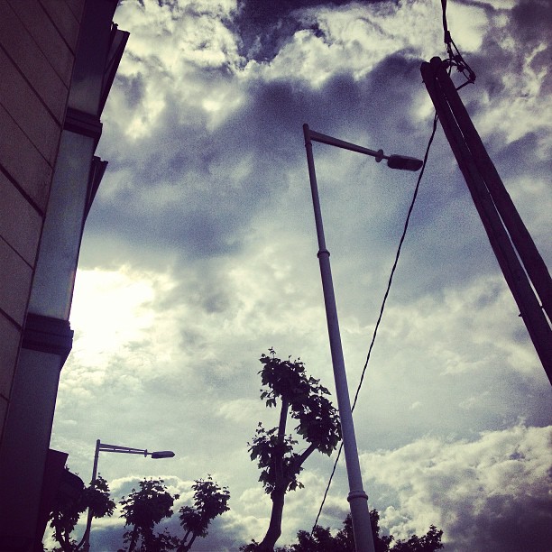 Cielo nublado con farolas y cables vistos desde la calle