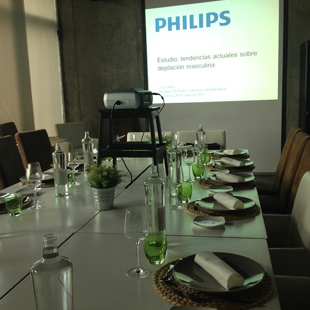 Pantalla de presentación de Philips sobre depilación masculina, en una sala con la mesa preparada
