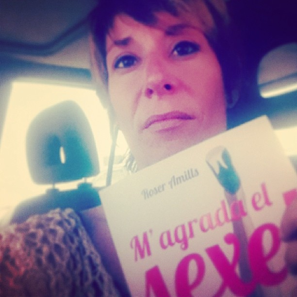 Mujer con un ejemplar de M'agrada el sexe! en el asiento de un coche