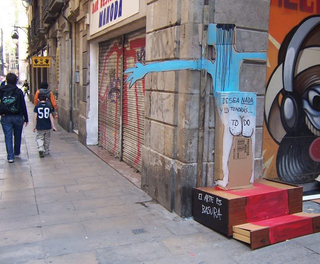 Obra callejera de Francisco de Pájaro sobre un embalaje de cartón y una caja, con el lema «El arte es basura», en una calle de Barcelona
