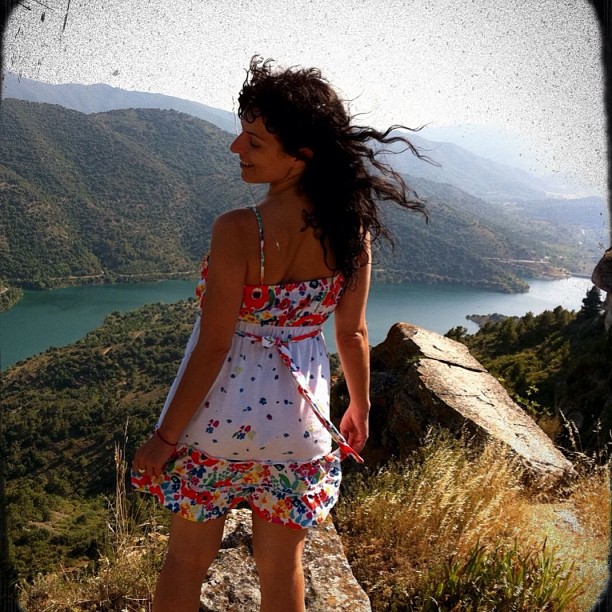 Roser Amills con vestido de flores sobre unas rocas ante un embalse entre montañas