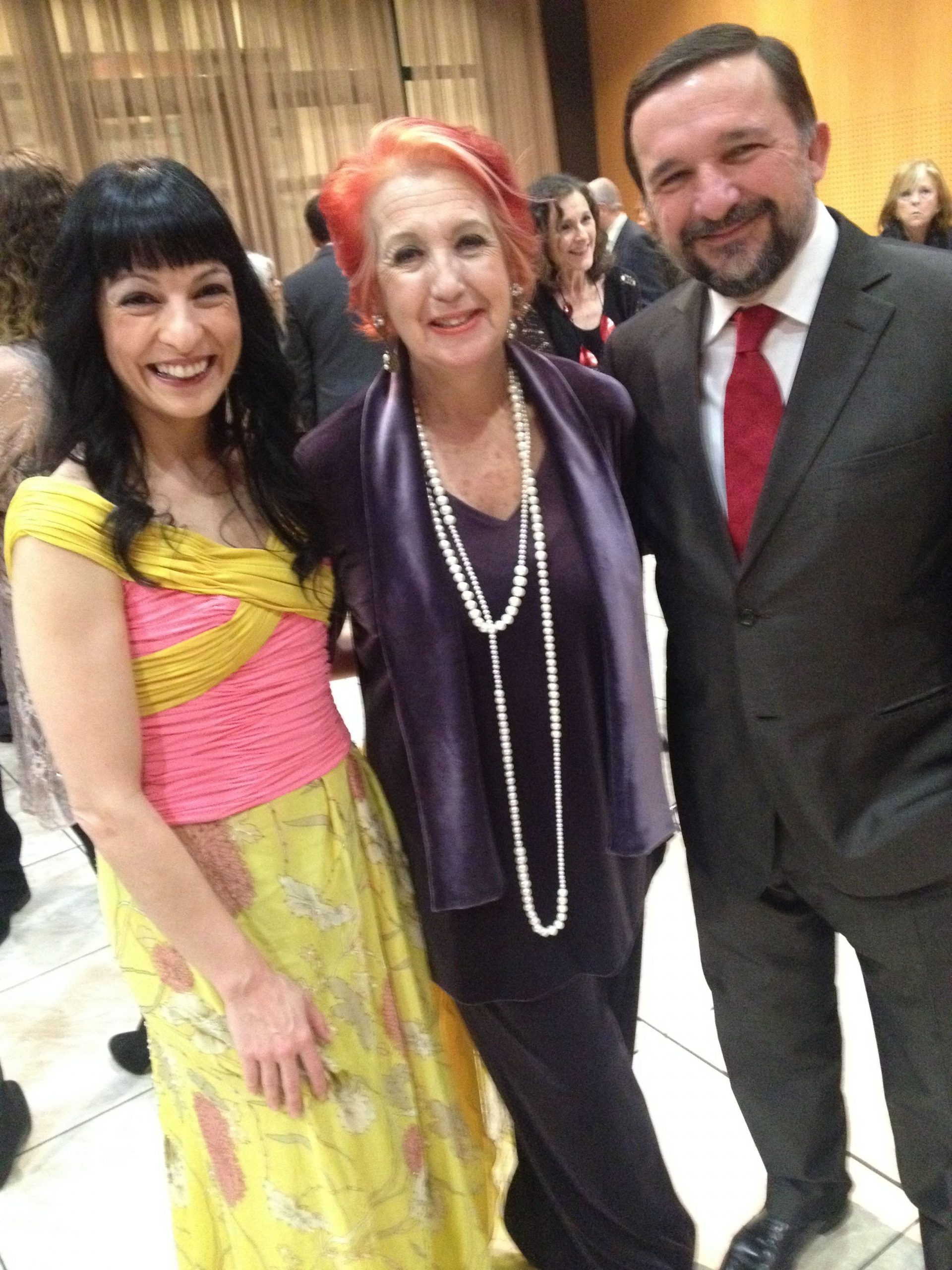 Roser Amills, con vestido amarillo y rosa, junto a Rosa Maria Calaf y Sergio Vila-Sanjuán en los Premios APEI 2014