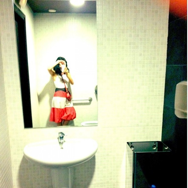 Roser Amills se fotografía en el espejo de un lavabo, con camiseta blanca y falda roja