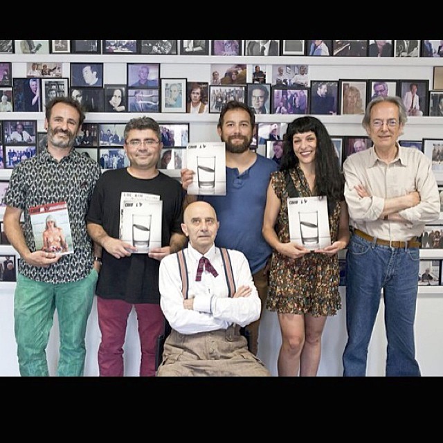 Seis personas posan delante de una pared de fotografías enmarcadas, varias con ejemplares de Canibaal; Roser Amills, con vestido de flores y flequillo, sostiene uno