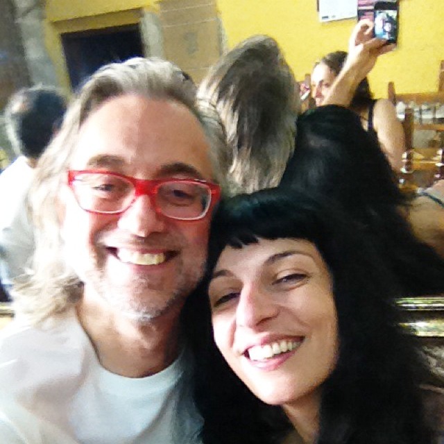 Selfie de Roser Amills y Víctor Amela, sonriendo juntos en un local de paredes amarillas