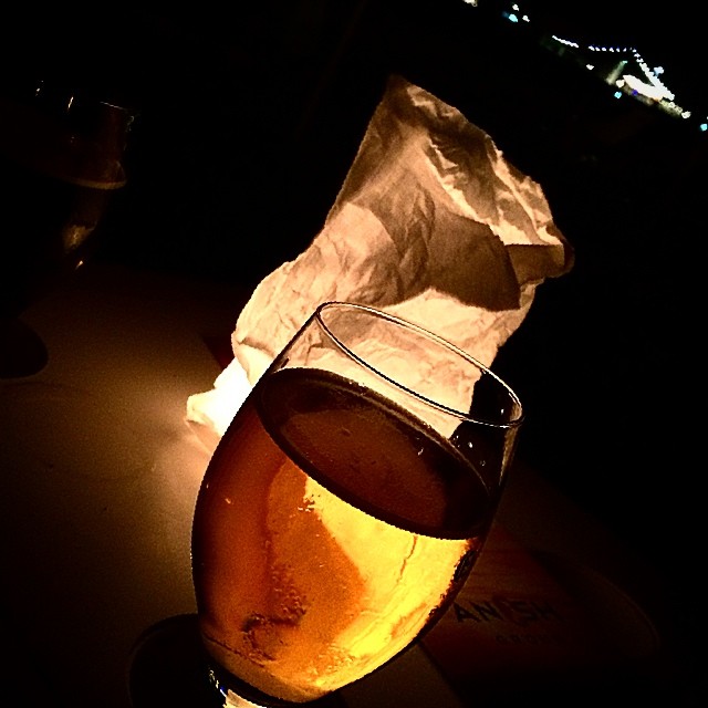 Copa de cerveza en la penumbra, junto a un farolillo de papel encendido