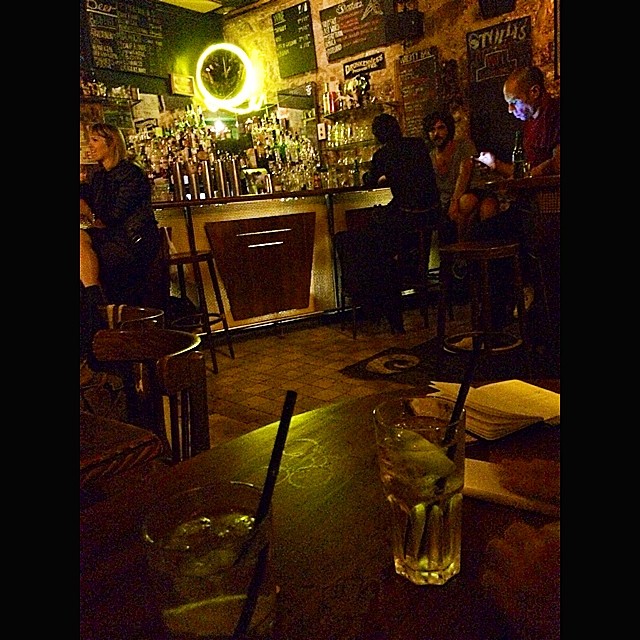 Barra de un bar nocturno de París con una mesa y dos vasos en primer plano