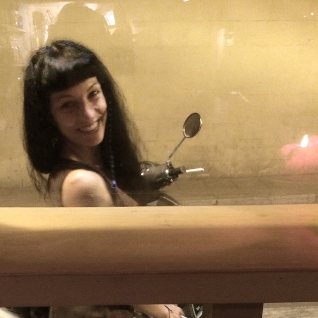 Roser Amills sonriendo tras un cristal, junto a una moto, en el barrio de Gràcia