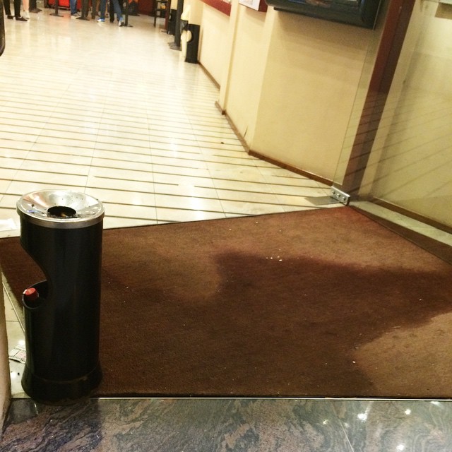 Entrada buida d'uns cinemes amb una catifa vermella i un cendrer de peu negre