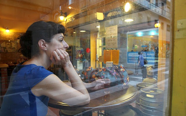 Roser Amills sentada tras el cristal de un bar, con la mano en la mejilla