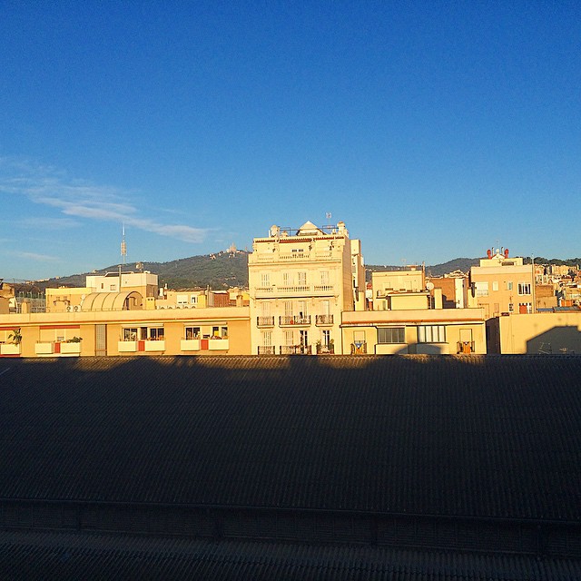 Edificios iluminados por el sol de la mañana bajo un cielo azul, con una montaña al fondo