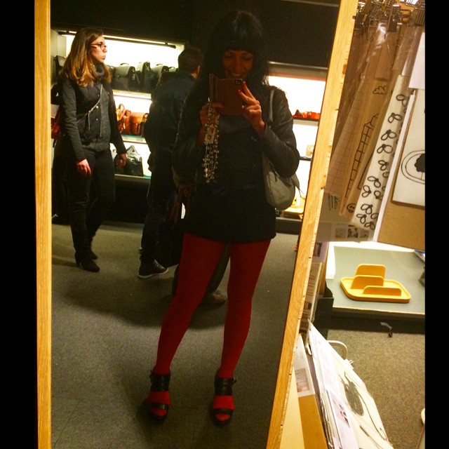 Roser Amills haciéndose un selfi en un espejo, con medias rojas y vestido negro, en una tienda