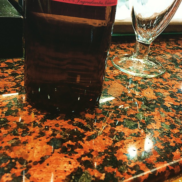 Botella de cerveza y una copa sobre una mesa de granito rojizo