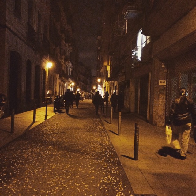 Calle del centro de Barcelona de noche, con farolas encendidas y varias personas caminando