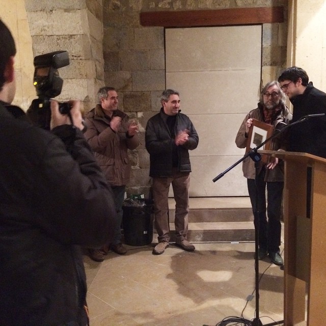 Entrega del premi del Patronat de Turisme de Morella, amb un fotògraf, dos homes aplaudint i Víctor Amela a un faristol