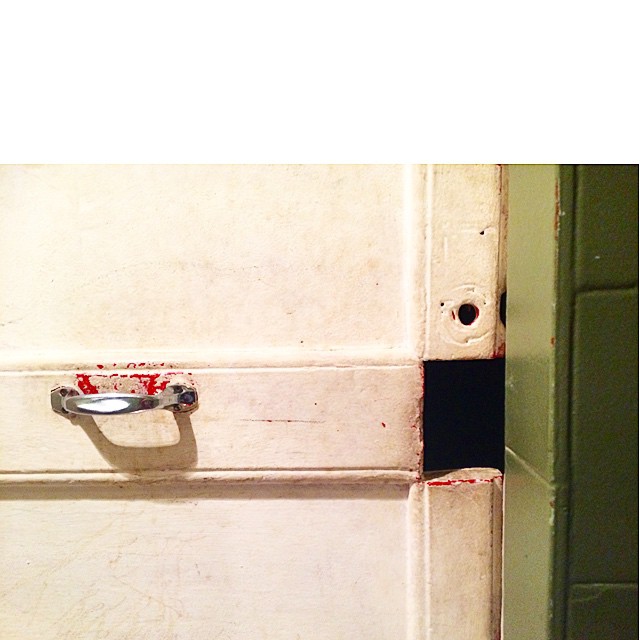 Puerta blanca de un lavabo con un tirador y un agujero en lugar de cerradura